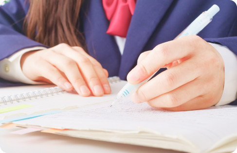 ノートにシャープペンで書き込む制服姿の生徒の手元