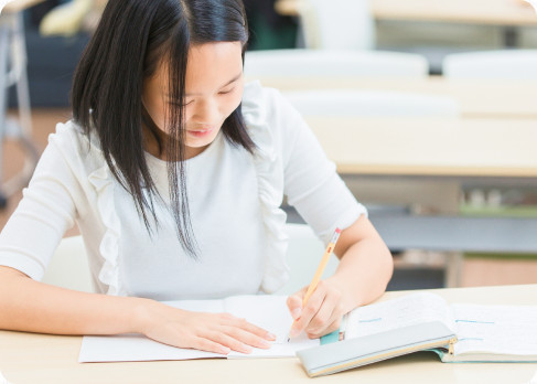 教室の机でノートに向かって学習する女子生徒
