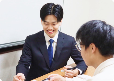 机をはさんで笑顔で生徒と話す講師
