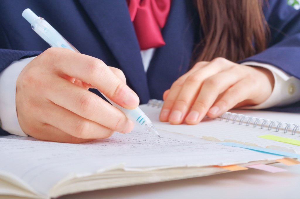 ノートにシャープペンで書き込みながら勉強する制服姿の生徒の手元